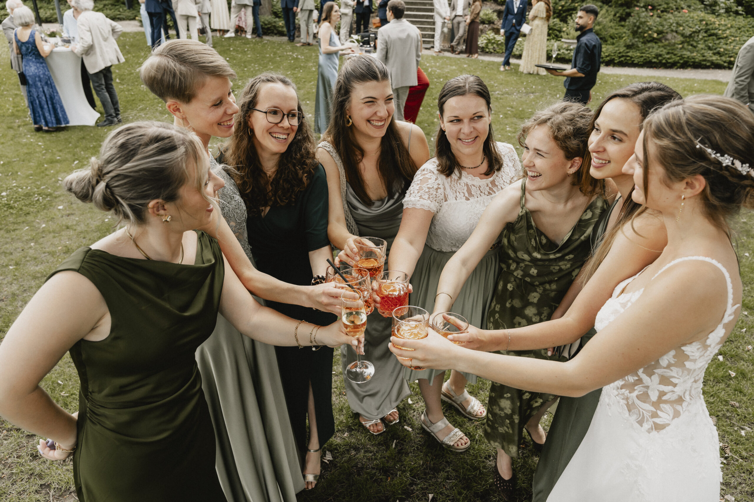 Alexa stößt beim Hochzeitsempfang im Garten mit ihren Gästen an