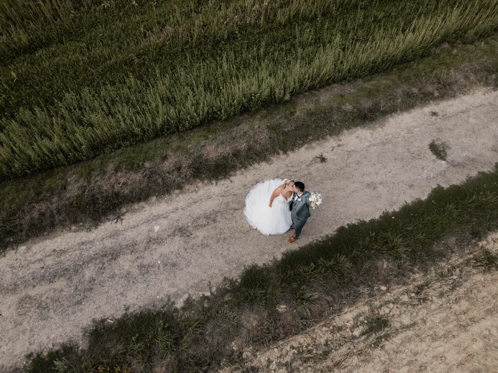 Luftaufnahme von Laura und Philipp auf einem hellen Weg zwischen Wiese und Feld.